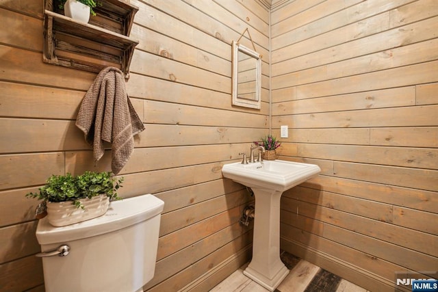 half bath with toilet and wooden walls