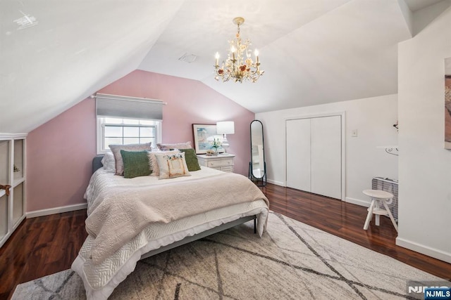 bedroom with a closet, baseboards, wood finished floors, and vaulted ceiling