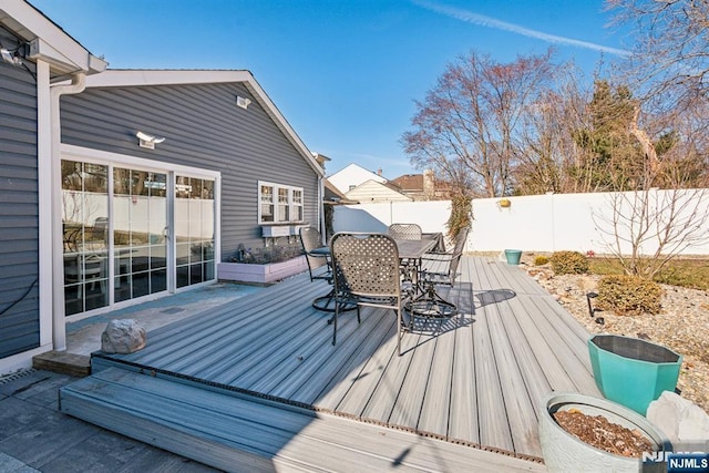 wooden terrace with outdoor dining space and a fenced backyard