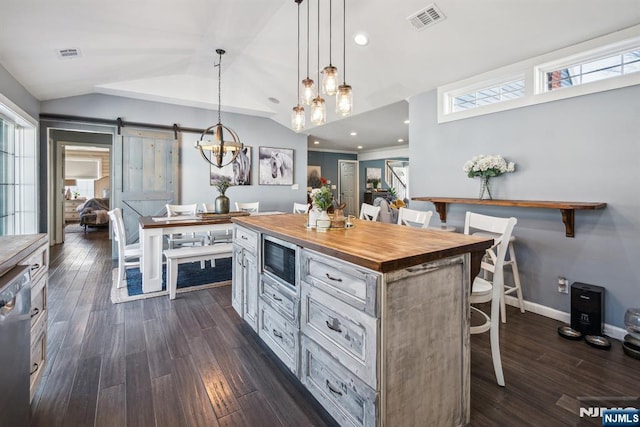 kitchen with visible vents, butcher block countertops, a breakfast bar area, a barn door, and stainless steel appliances