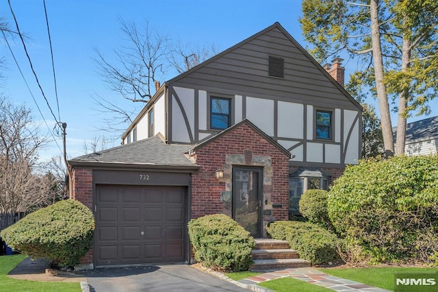 tudor house with an attached garage, brick siding, roof with shingles, stucco siding, and a chimney