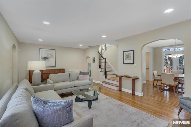 living area featuring light wood-type flooring, arched walkways, and recessed lighting