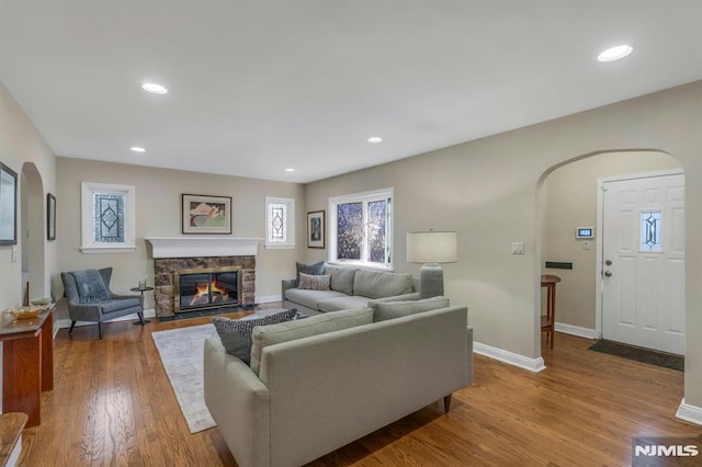 living room featuring arched walkways, recessed lighting, baseboards, and wood finished floors