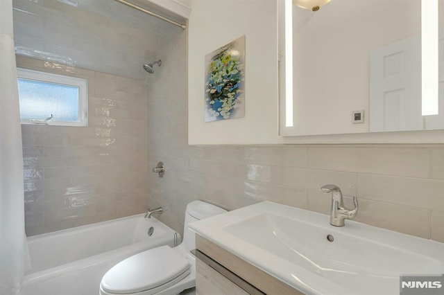 bathroom featuring toilet, bathtub / shower combination, tile walls, and vanity