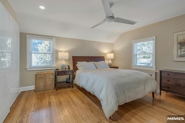 bedroom with lofted ceiling, multiple windows, and wood finished floors