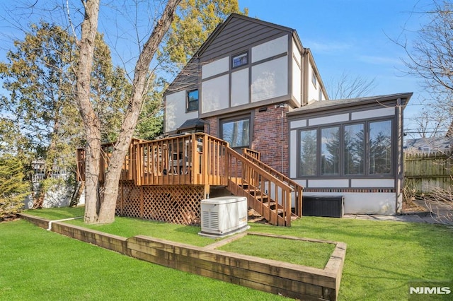 back of property featuring a deck, a yard, brick siding, and fence