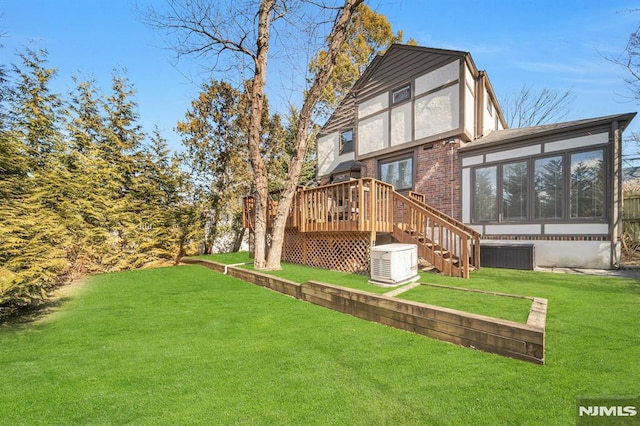 back of property featuring a wooden deck, a sunroom, stairway, a yard, and brick siding