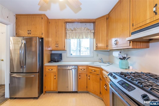 kitchen featuring appliances with stainless steel finishes, under cabinet range hood, light countertops, light floors, and a sink