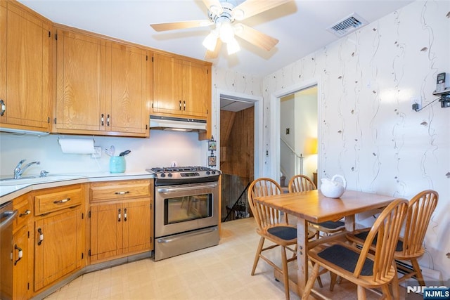 kitchen with under cabinet range hood, stainless steel appliances, a sink, visible vents, and light floors