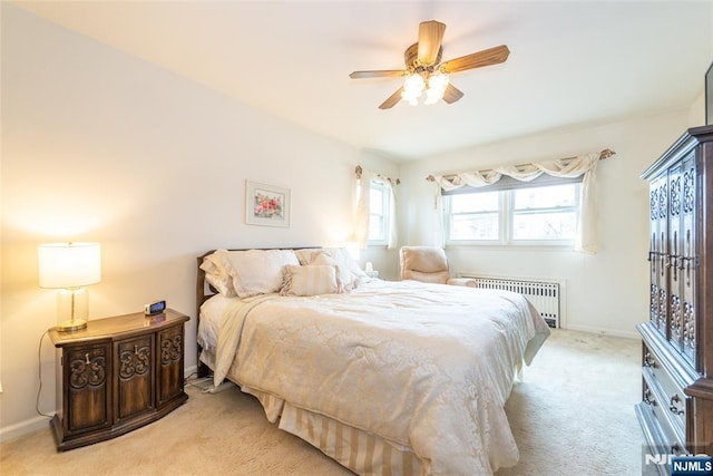 carpeted bedroom with radiator heating unit, baseboards, and ceiling fan