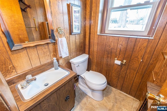 bathroom with tile patterned flooring, vanity, toilet, and wooden walls