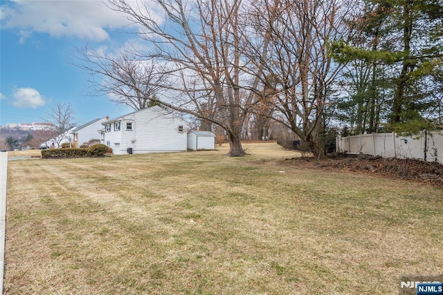 view of yard featuring an outbuilding, a storage unit, and fence