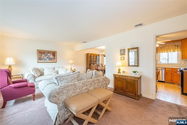 living room featuring light colored carpet, visible vents, and an inviting chandelier