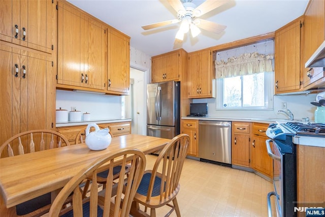 kitchen with ceiling fan, appliances with stainless steel finishes, brown cabinets, light countertops, and light floors