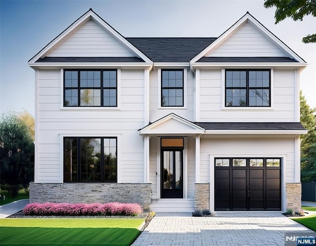 view of front of house with an attached garage, stone siding, and decorative driveway