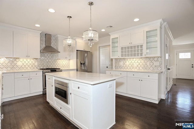 kitchen with wall chimney exhaust hood, dark wood finished floors, white cabinets, and stainless steel appliances