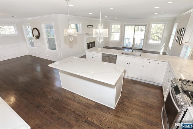 kitchen featuring dark wood-style floors, appliances with stainless steel finishes, light stone counters, and ornamental molding