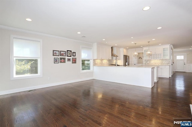 unfurnished living room featuring a sink, plenty of natural light, dark wood finished floors, and crown molding