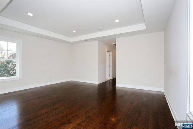 spare room featuring baseboards, a tray ceiling, dark wood-style flooring, and recessed lighting