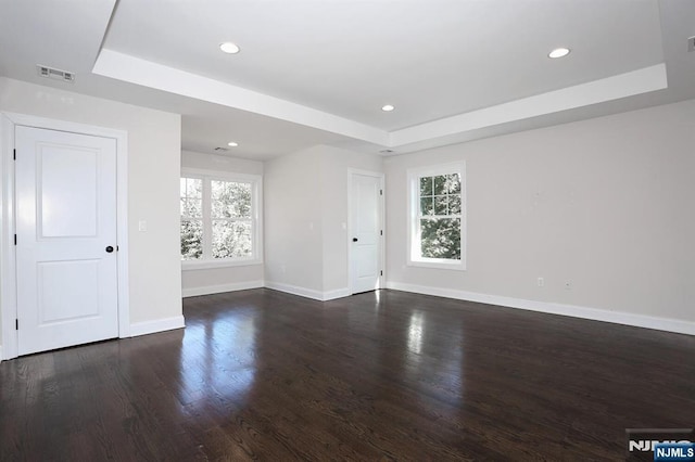 empty room with a tray ceiling, recessed lighting, and baseboards