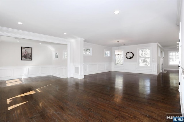 unfurnished living room with ornamental molding, a decorative wall, wood finished floors, and recessed lighting