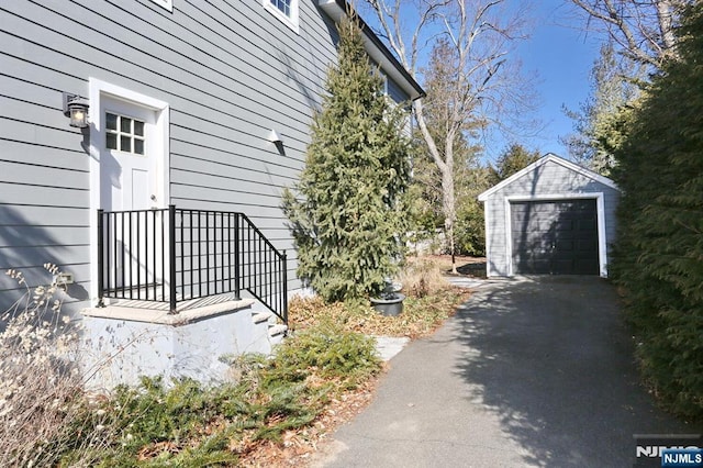 view of home's exterior featuring a detached garage, aphalt driveway, and an outbuilding