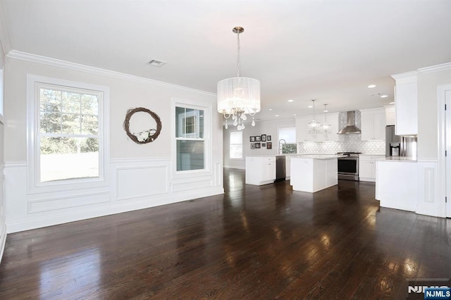 unfurnished living room with visible vents, dark wood finished floors, a wainscoted wall, ornamental molding, and an inviting chandelier