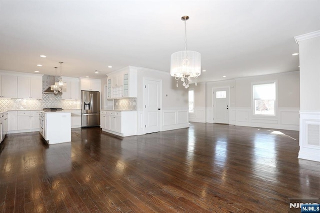 unfurnished living room with ornamental molding, dark wood-style flooring, and a notable chandelier