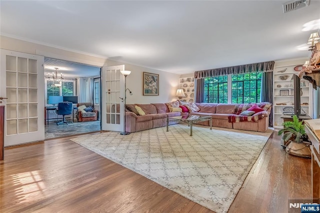 living area with french doors, wood finished floors, visible vents, and crown molding