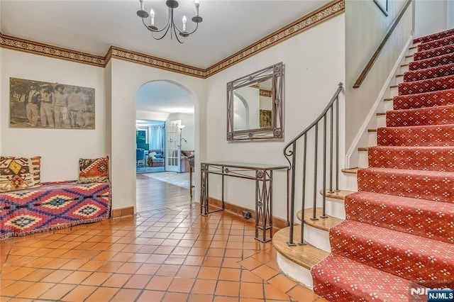 interior space with arched walkways, baseboards, an inviting chandelier, tile patterned flooring, and crown molding