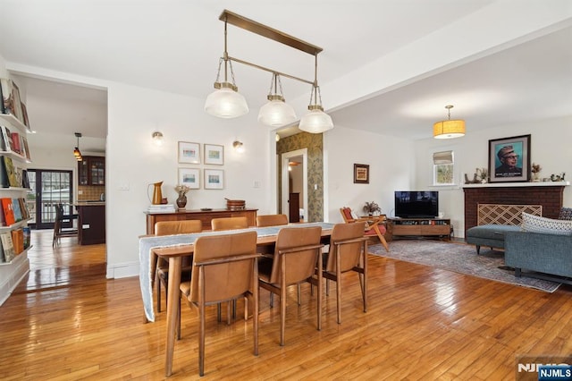 dining space with light wood-style floors, a fireplace, and baseboards