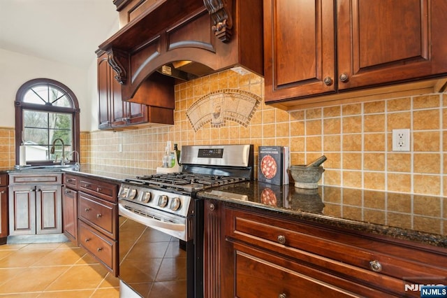 kitchen featuring light tile patterned floors, dark stone counters, decorative backsplash, and gas stove