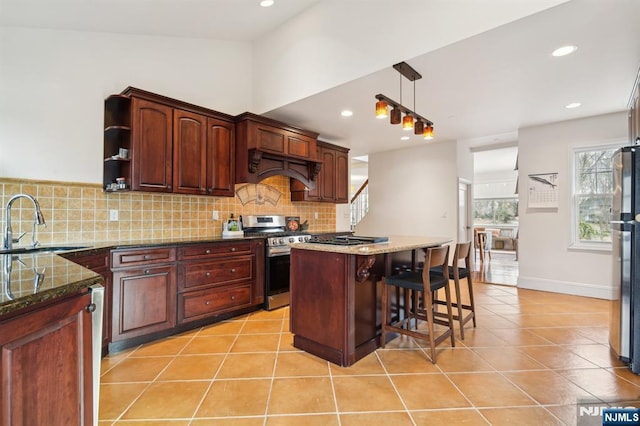 kitchen with appliances with stainless steel finishes, light tile patterned flooring, a sink, and tasteful backsplash