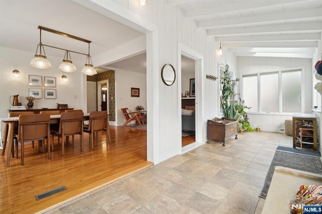 dining room featuring light wood-style floors, visible vents, beamed ceiling, and baseboards