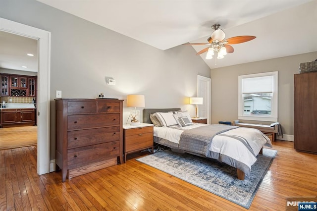 bedroom featuring light wood-style floors, vaulted ceiling, and a ceiling fan