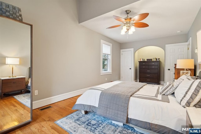 bedroom with a ceiling fan, light wood-style flooring, visible vents, and baseboards