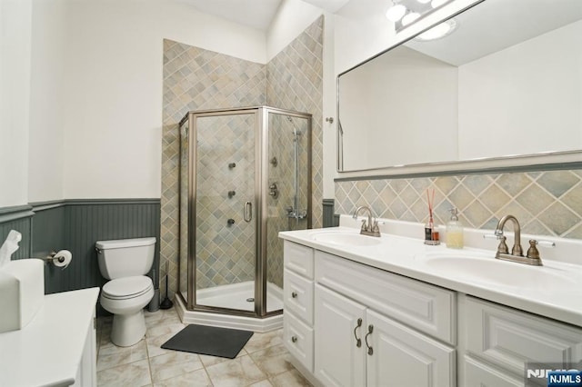 full bath featuring a shower stall, a sink, and wainscoting