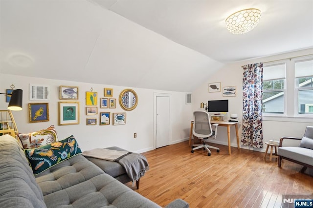 office featuring light wood-style floors, visible vents, vaulted ceiling, and baseboards