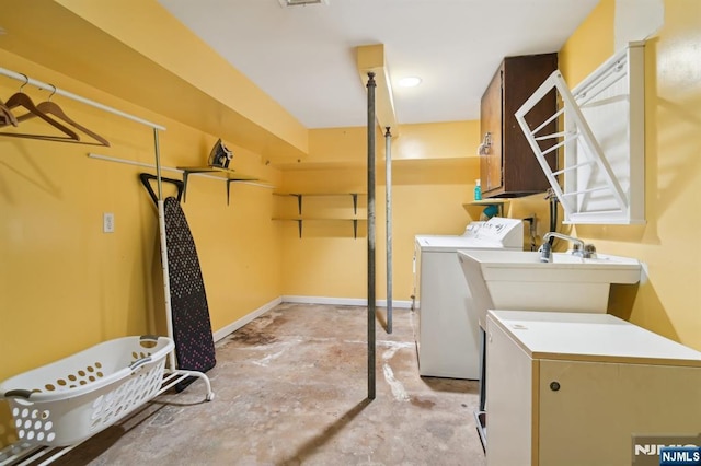 clothes washing area with washing machine and dryer, cabinet space, and baseboards