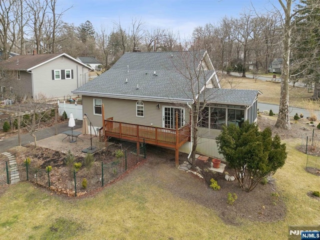 back of property featuring a patio, a shingled roof, a wooden deck, and a sunroom