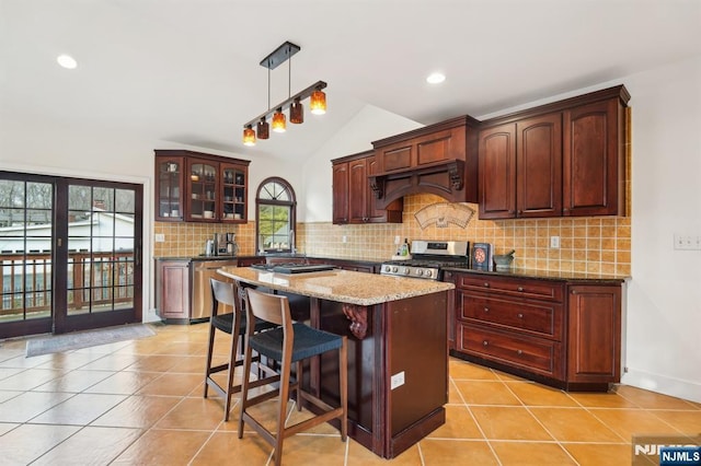 kitchen featuring light tile patterned floors, tasteful backsplash, a center island, vaulted ceiling, and stainless steel appliances