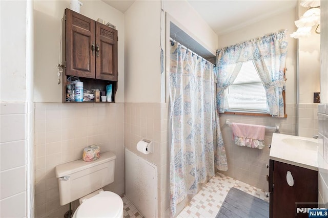 full bathroom featuring wainscoting, toilet, curtained shower, vanity, and tile walls