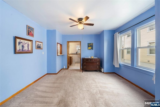 carpeted bedroom featuring ensuite bath, a baseboard radiator, baseboards, and a ceiling fan