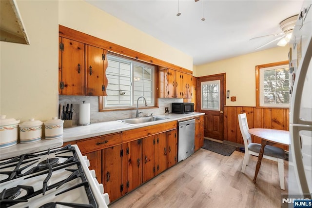 kitchen featuring brown cabinets, light countertops, a sink, black microwave, and dishwasher