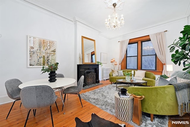 living area with a chandelier, ornamental molding, and wood-type flooring