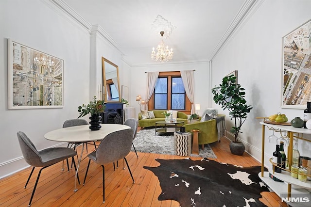 dining room with baseboards, a notable chandelier, crown molding, and hardwood / wood-style flooring