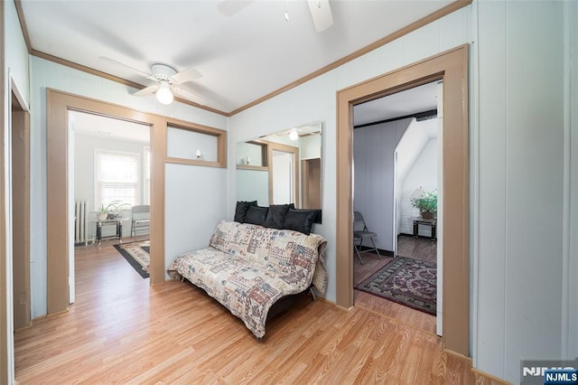 interior space with a ceiling fan, radiator, crown molding, and light wood finished floors