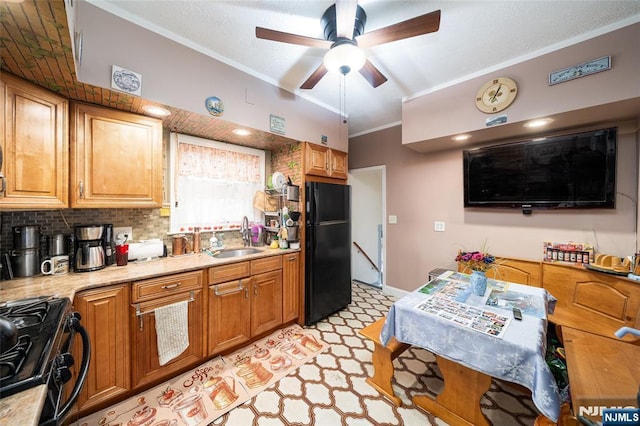 kitchen with a sink, decorative backsplash, black appliances, light countertops, and ornamental molding