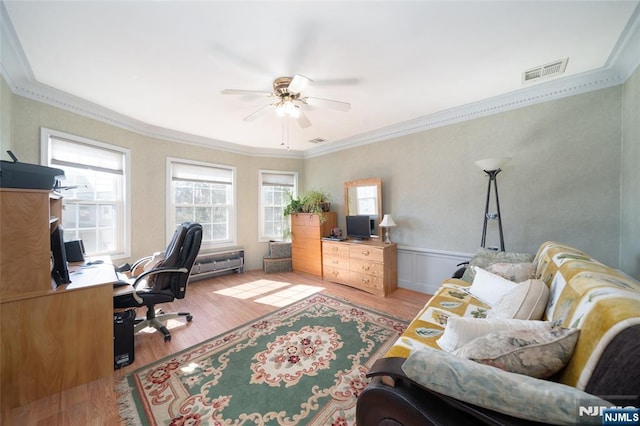 office space with visible vents, a wainscoted wall, ornamental molding, wood finished floors, and a ceiling fan