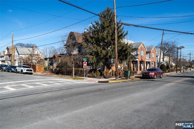 view of road with sidewalks, a residential view, curbs, and traffic signs